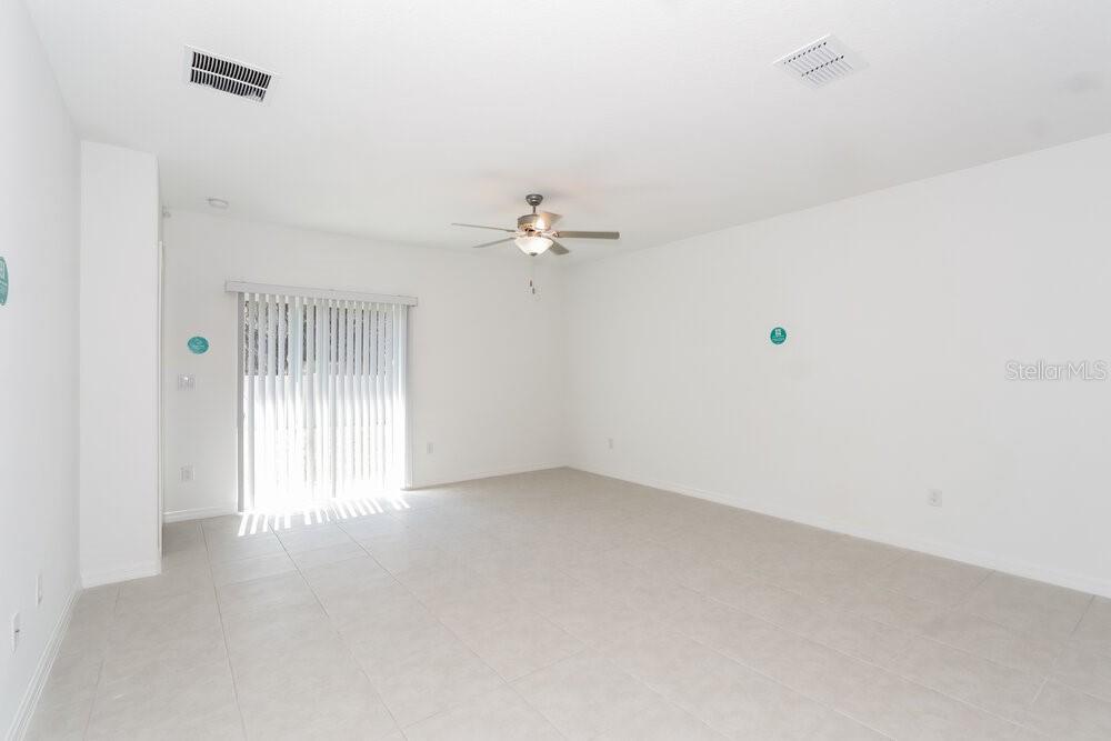 An empty room with white walls, tile flooring, a ceiling fan, and sliding glass doors — 17994 BLISSFUL STARS DRIVE, LUTZ, FL