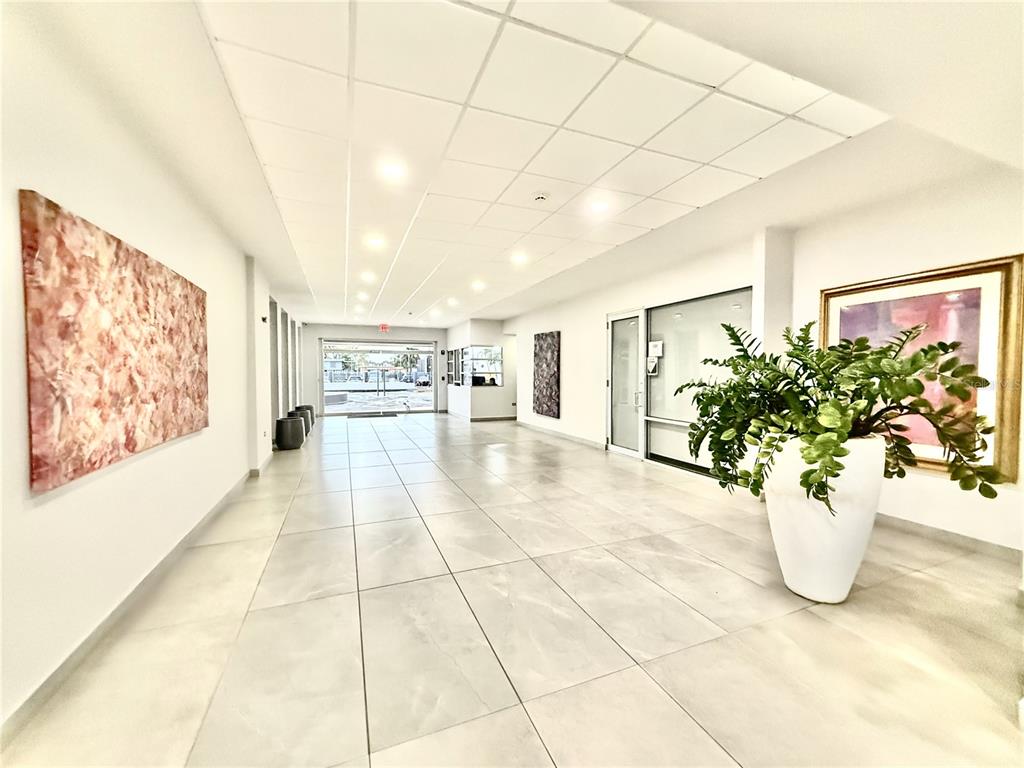 A bright, tiled lobby features a large potted plant, abstract wall art, and recessed lighting — 3103 AV. ISLA VERDE UNIT 306, CAROLINA, PR
