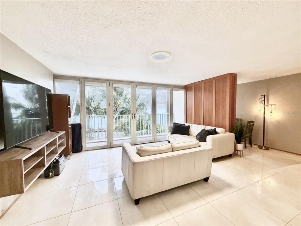 A living room features white tile floors, a white sofa, and glass doors to a balcony — 3103 AV. ISLA VERDE UNIT 306, CAROLINA, PR