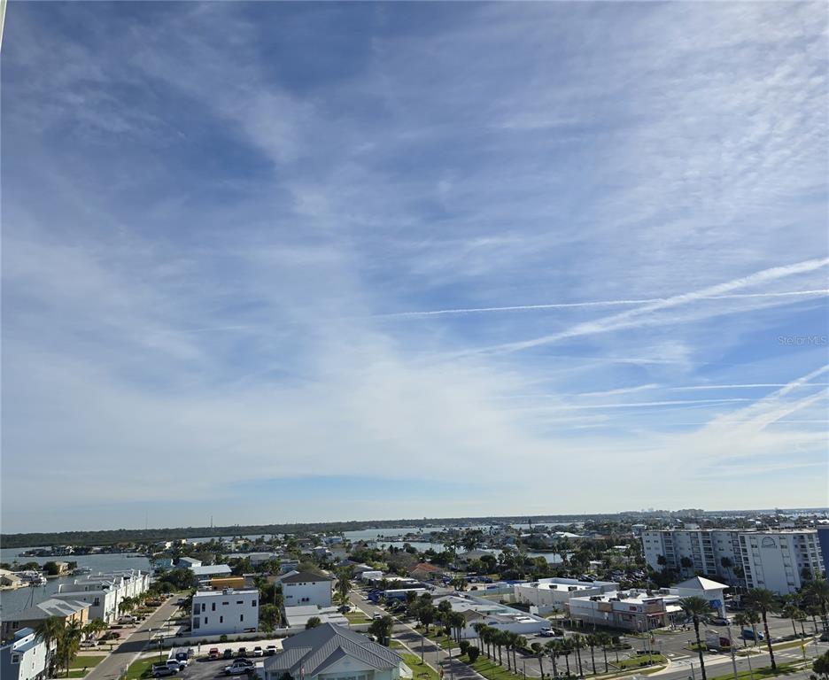 An elevated view of a coastal neighborhood with houses, palm trees, and a blue sky — 17408 GULF BOULEVARD UNIT 1003, REDINGTON SHORES, FL