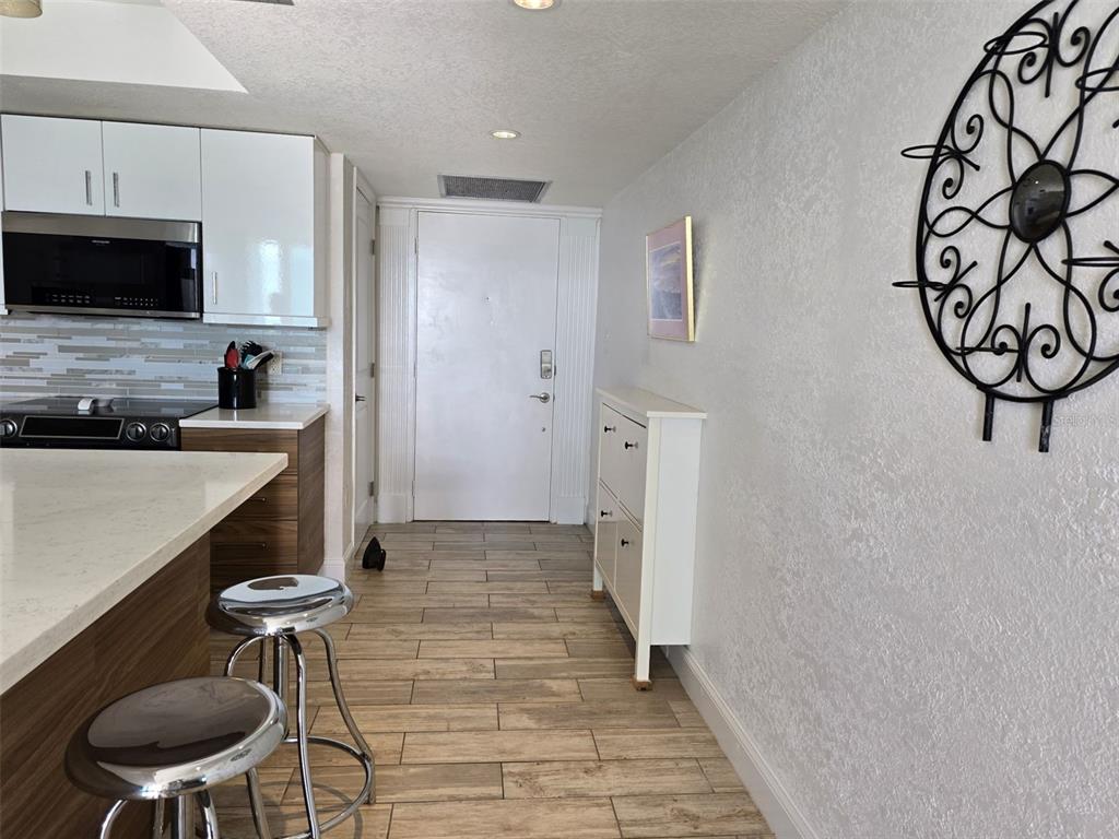 A kitchen with a breakfast bar, white cabinets, and a white door in the background — 17408 GULF BOULEVARD UNIT 1003, REDINGTON SHORES, FL