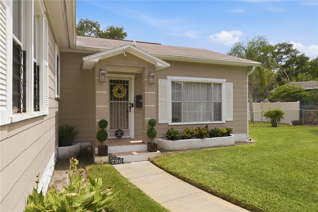 A tan house exterior features a front porch, a walkway, and a small garden bed — 726 17TH AVENUE S, ST PETERSBURG, FL