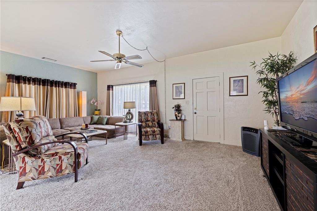 A living room features a sectional sofa, patterned armchairs, a ceiling fan, and carpeted flooring — 726 17TH AVENUE S, ST PETERSBURG, FL
