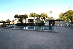 A rectangular swimming pool is surrounded by a paved patio and palm trees — 255 MISSION TRAIL S UNIT J, VENICE, FL