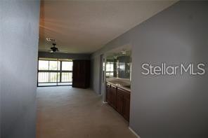 A room with gray walls, carpeted flooring, and a wooden vanity with a mirror — 255 MISSION TRAIL S UNIT J, VENICE, FL