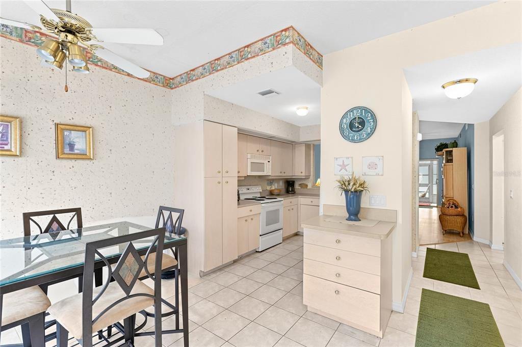 A kitchen with light wood cabinets and tile flooring opens into a dining area — 5800 SABAL TRACE DRIVE UNIT 105, NORTH PORT, FL