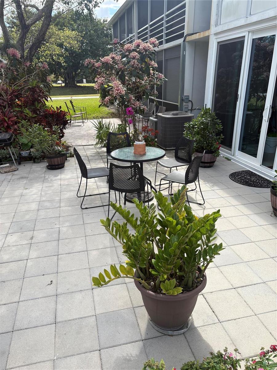 A paved patio features a small dining set, potted plants, and a view of the yard — 211 N Oakridge # 211, Deerfield Beach FL 33442, DEERFIELD BEACH, FL