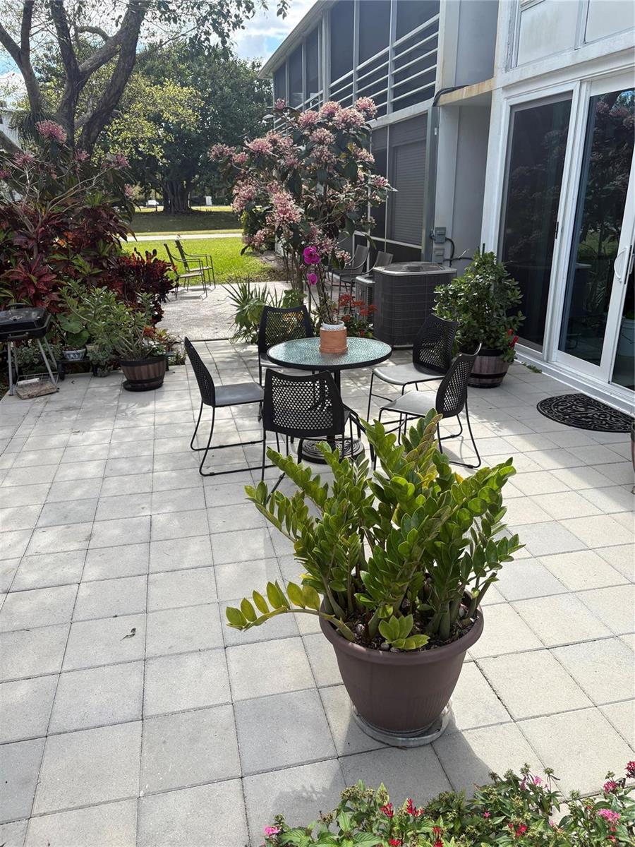 A patio features a dining set, potted plants, and a grill on a paved surface — 211 N Oakridge # 211, Deerfield Beach FL 33442, DEERFIELD BEACH, FL