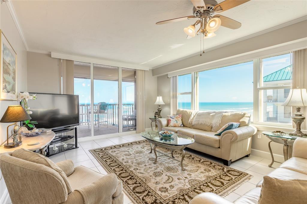 A living room with tile floors, a beige sofa, and a balcony overlooking the ocean — 4631 S ATLANTIC AVENUE UNIT 8607, PORT ORANGE, FL