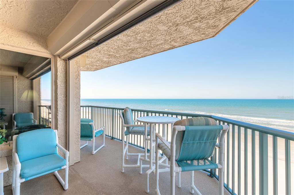 A balcony with patio furniture overlooks the ocean under a clear blue sky — 4631 S ATLANTIC AVENUE UNIT 8607, PORT ORANGE, FL