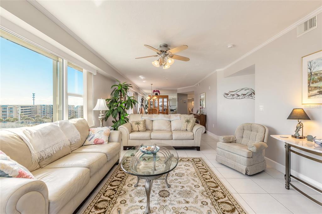 A living room features light-colored sofas, a glass coffee table, and a large window view — 4631 S ATLANTIC AVENUE UNIT 8607, PORT ORANGE, FL