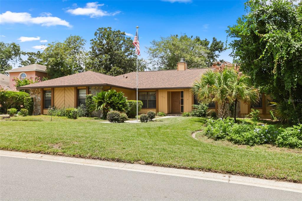 A single-story house with a brown roof, stone accents, and a front yard with trees — 1573 SKYE COURT, APOPKA, FL