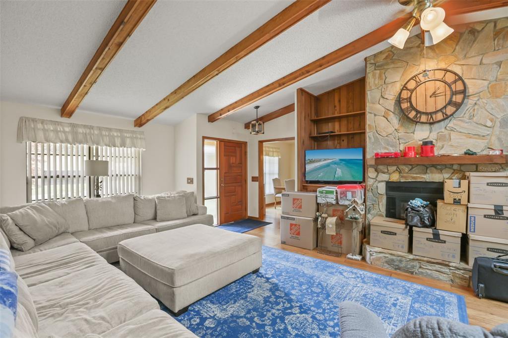 A living room features a stone fireplace, exposed wood ceiling beams, and a large sectional sofa — 1573 SKYE COURT, APOPKA, FL