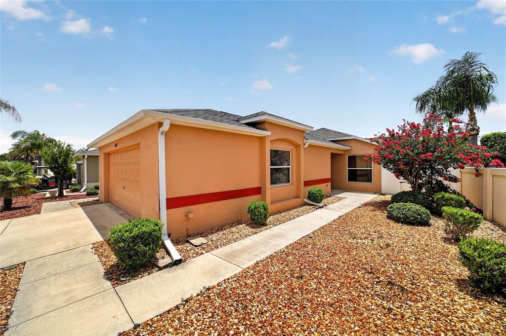 An exterior view of a peach-colored house with a garage and gravel landscaping — 308 ALMERIA STREET, THE VILLAGES, FL