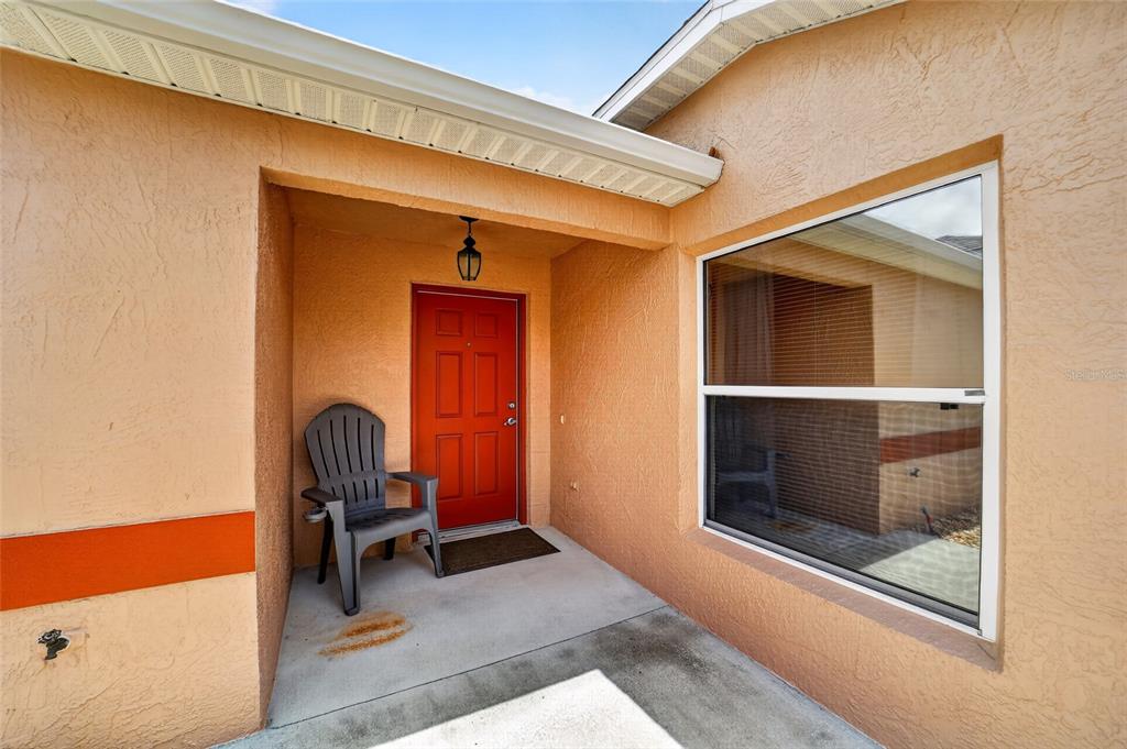 A front entryway features a red door, a gray chair, and a large window — 308 ALMERIA STREET, THE VILLAGES, FL