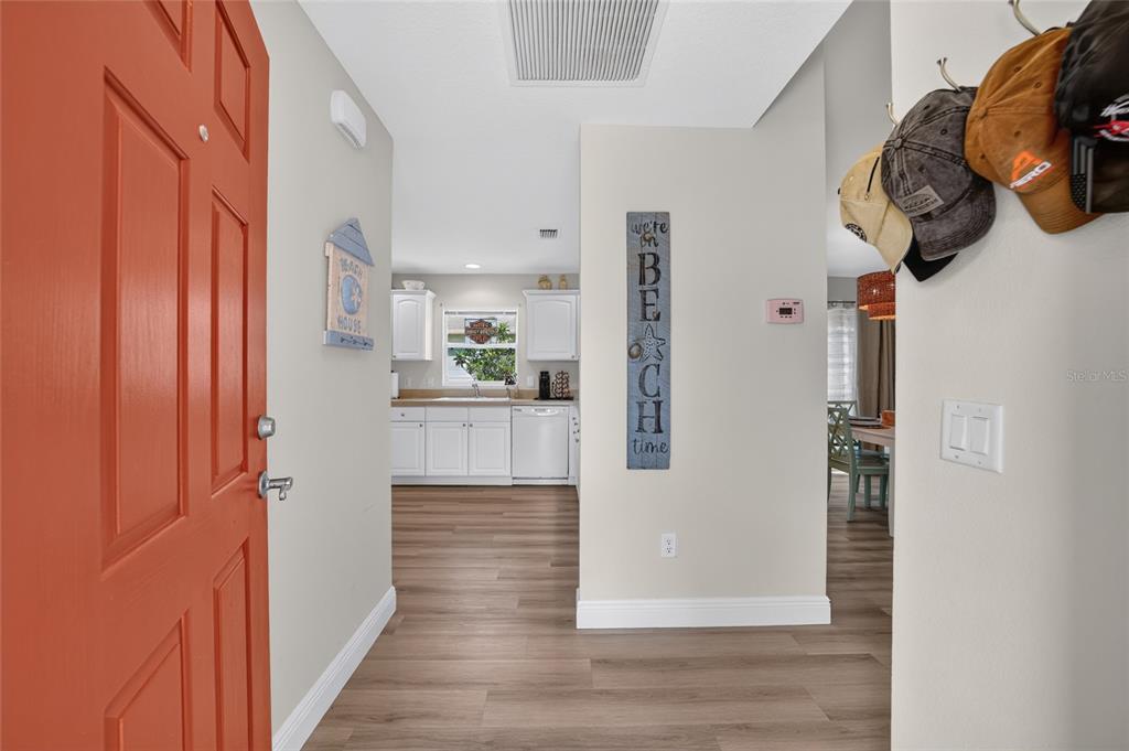 An entryway with a coral door leads into a kitchen with white cabinets and flooring — 308 ALMERIA STREET, THE VILLAGES, FL
