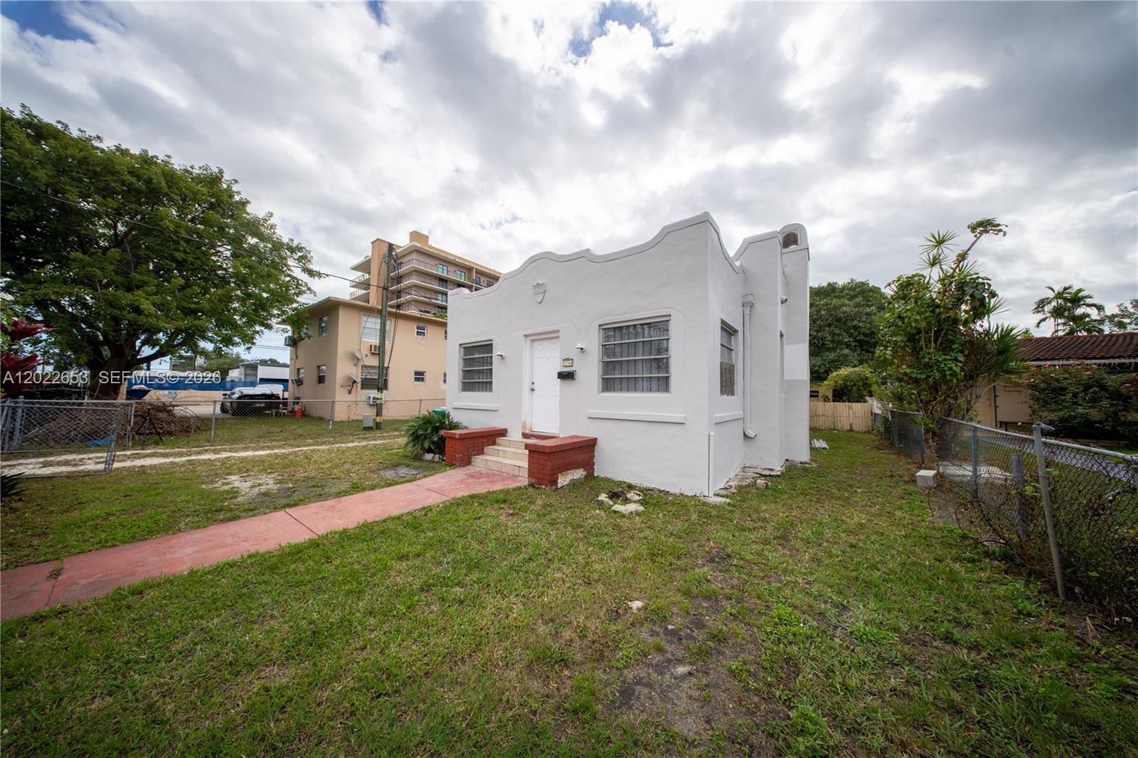 A white, single-story stucco house with a curved parapet roof stands on a grassy lot — 2744 SW 16th Ter, Miami FL 33145, MIAMI, FL