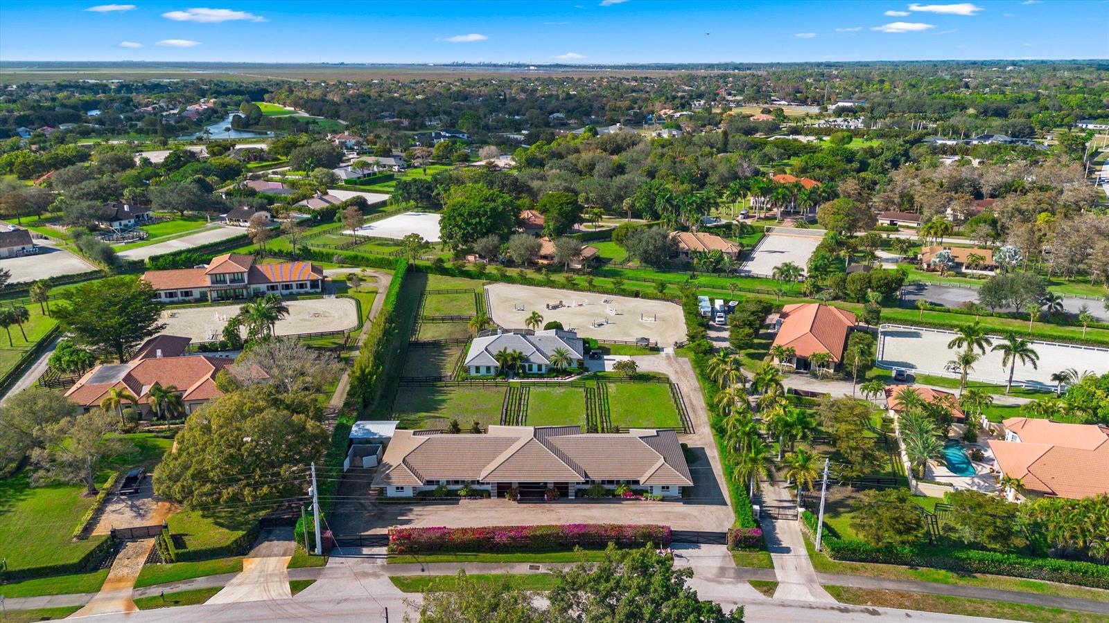 An aerial view of a residential equestrian property featuring multiple houses, stables, and riding arenas — 14371 Wellington Trace, Wellington FL 33414, WELLINGTON, FL