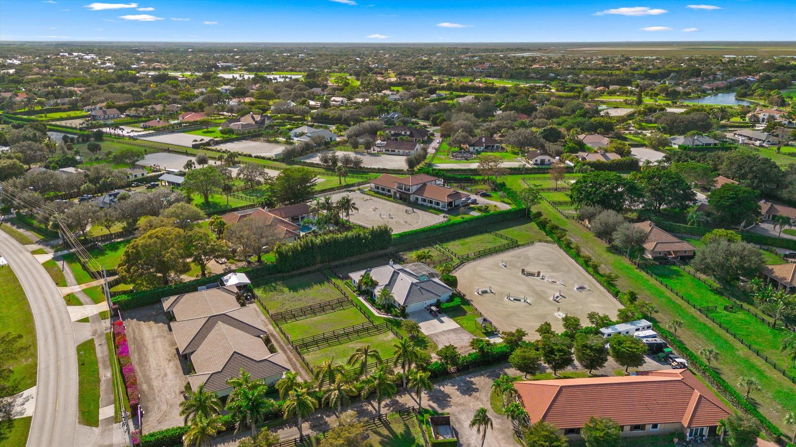 An aerial view of a residential equestrian property featuring multiple houses, stables, and riding arenas — 14371 Wellington Trace, Wellington FL 33414, WELLINGTON, FL