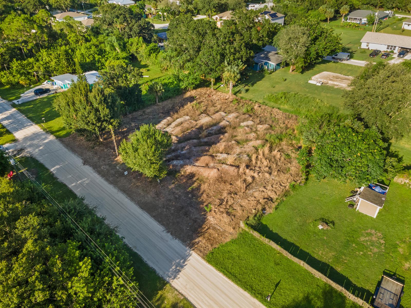 An aerial view shows a vacant, partially cleared residential lot bordered by a dirt road — 8720 92nd Avenue, Vero Beach FL 32967, VERO BEACH, FL