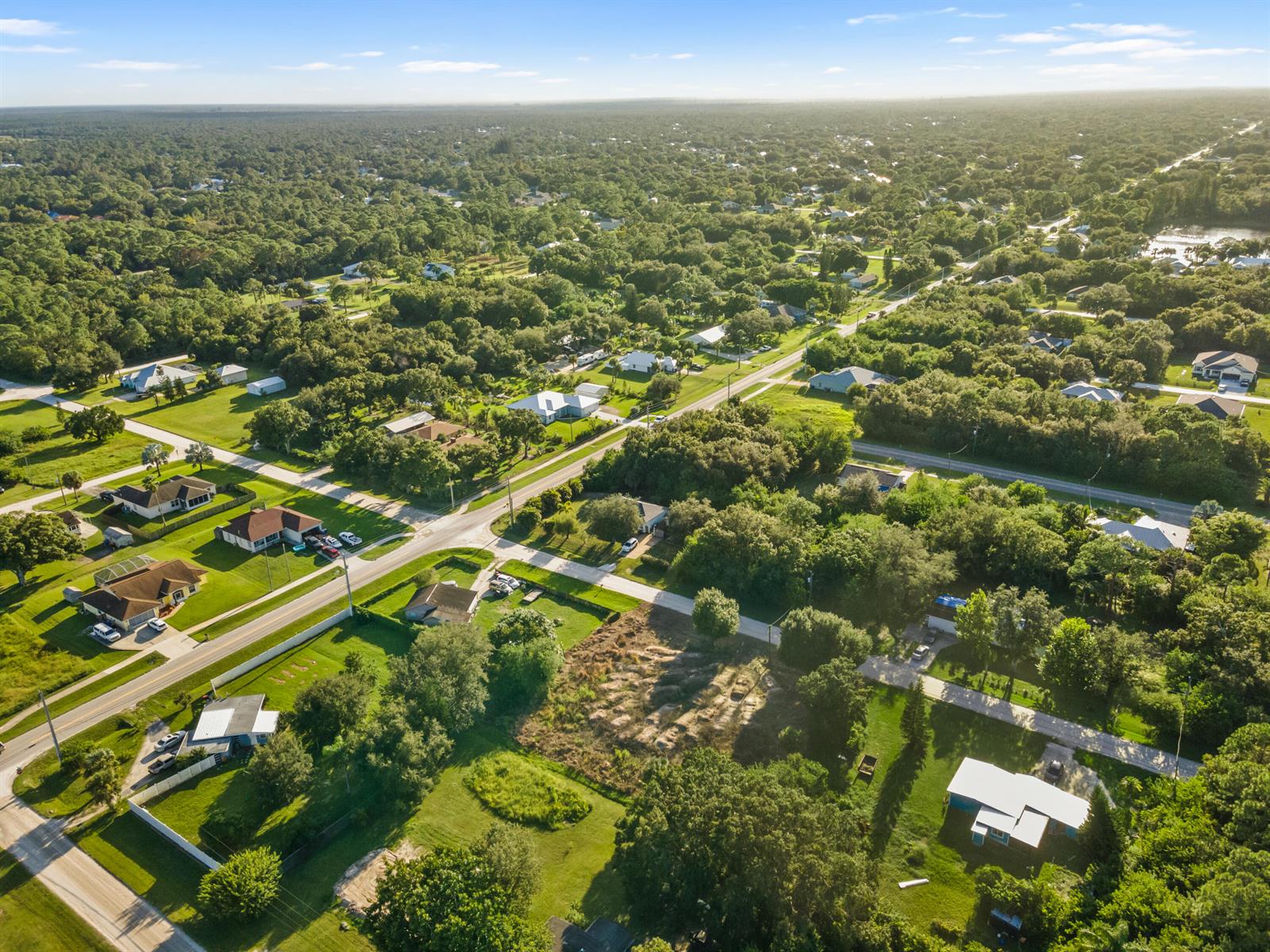 An aerial view shows a residential neighborhood with scattered houses surrounded by dense green trees — 8720 92nd Avenue, Vero Beach FL 32967, VERO BEACH, FL