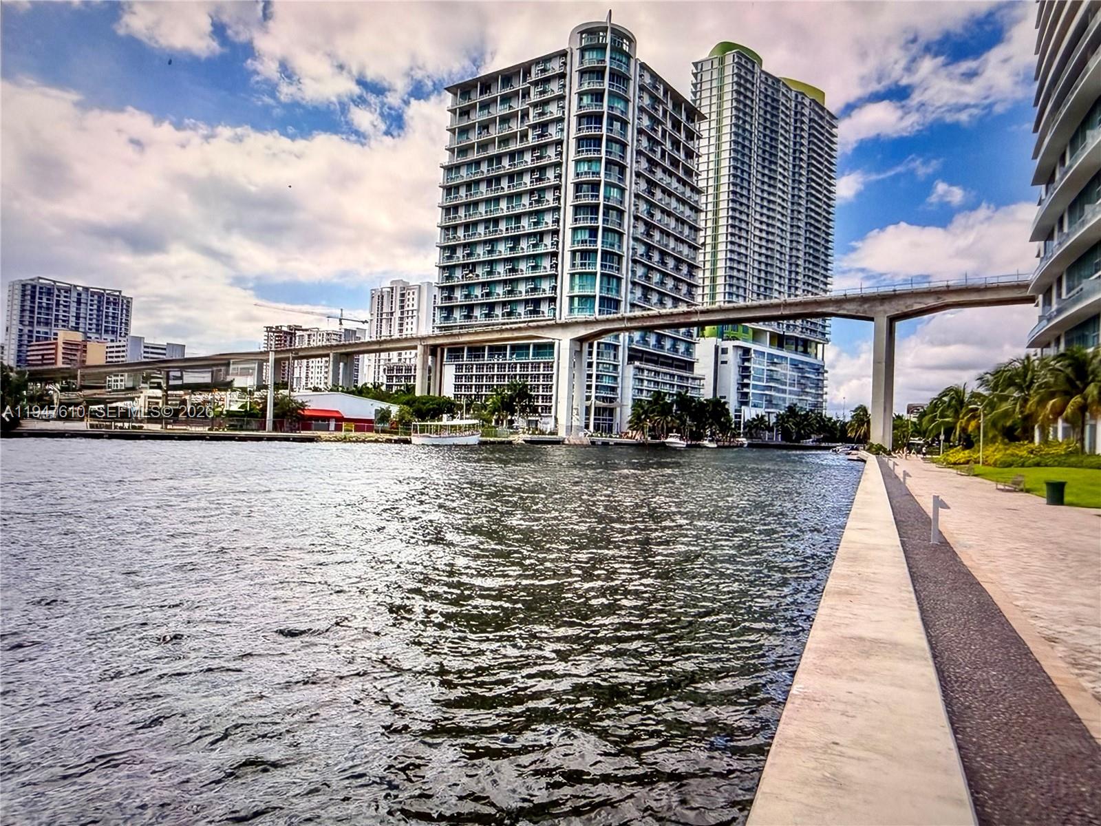 A view of a riverfront walkway with high-rise buildings and an elevated train track overhead — 92 SW 3rd St # 4709, Miami FL 33130, MIAMI, FL