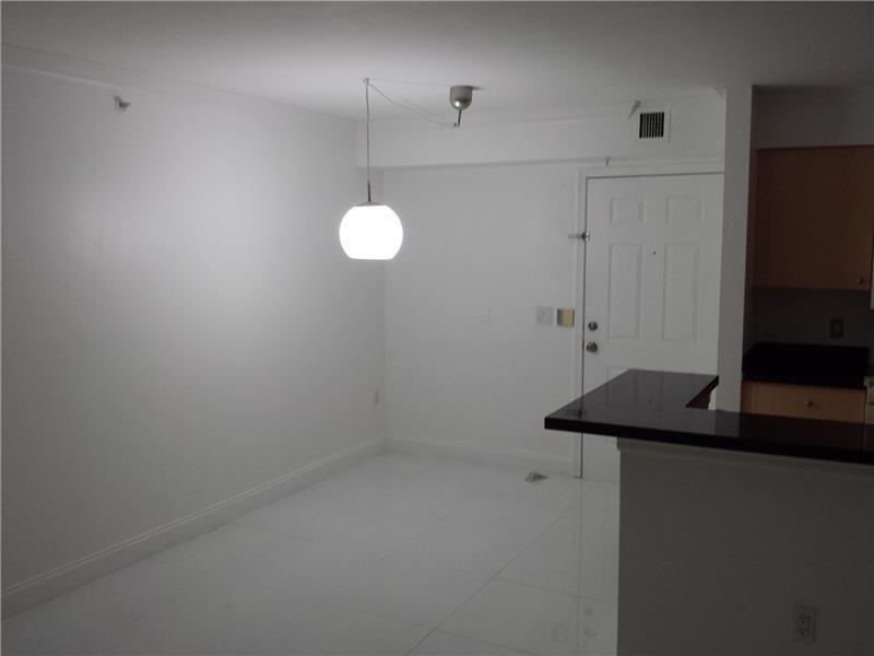 An empty dining area features white walls, white tile flooring, and a single pendant light — 2451 E Centergate Drive # 208, Miramar FL 33025, MIRAMAR, FL