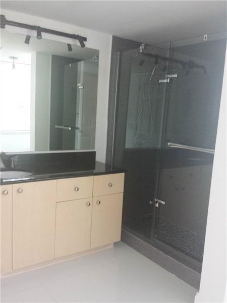 A bathroom features light wood cabinets, a black countertop, a large mirror, and a shower — 2451 E Centergate Drive # 208, Miramar FL 33025, MIRAMAR, FL