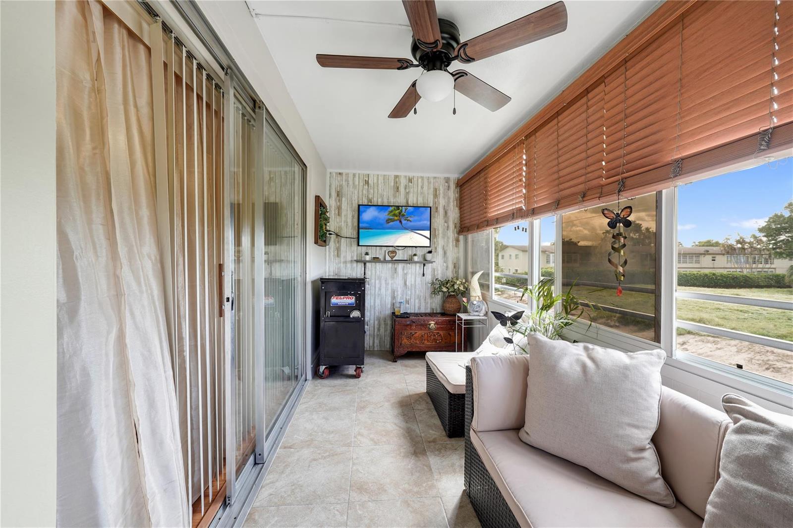 A sunroom features tile flooring, a ceiling fan, a wall-mounted television, and sliding glass doors — 551 NW 76th Terrace # 208, Margate FL 33063, MARGATE, FL