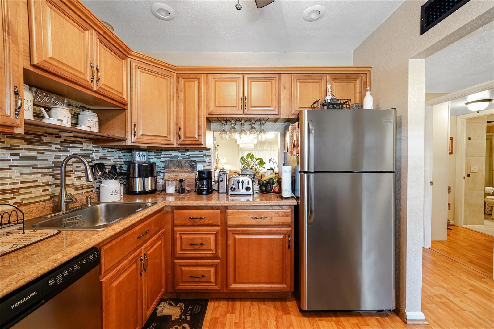 A kitchen features wood cabinets, stainless steel appliances, a tile backsplash, and granite countertops — 551 NW 76th Terrace # 208, Margate FL 33063, MARGATE, FL