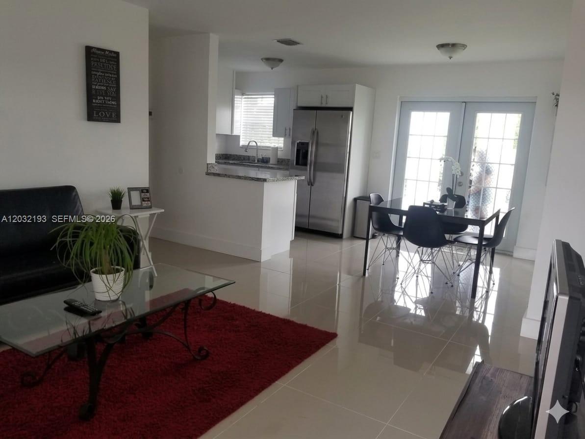 An open-concept living and dining area features tile floors, a kitchen, and glass doors — 1321 NW 199th St, Miami Gardens FL 33169, MIAMI GARDENS, FL