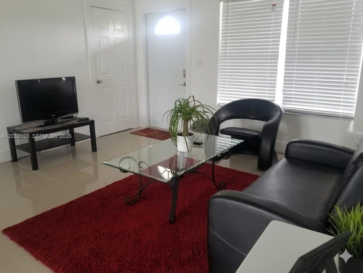 A living room features a glass coffee table, black leather furniture, and a red rug — 1321 NW 199th St, Miami Gardens FL 33169, MIAMI GARDENS, FL