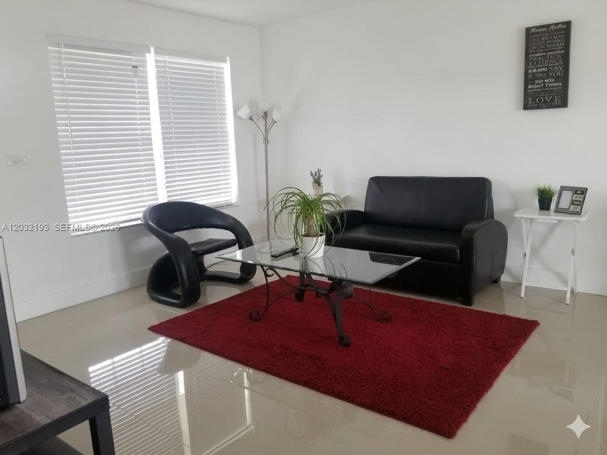 A living room features a black sofa, a modern chair, a glass coffee table, and red rug — 1321 NW 199th St, Miami Gardens FL 33169, MIAMI GARDENS, FL