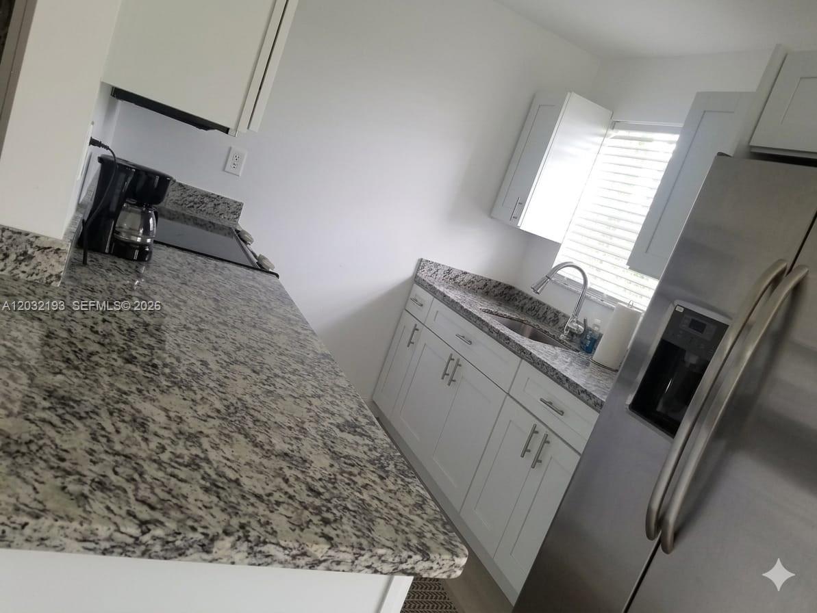 A kitchen features white cabinets, granite countertops, stainless steel appliances, and a window with blinds — 1321 NW 199th St, Miami Gardens FL 33169, MIAMI GARDENS, FL