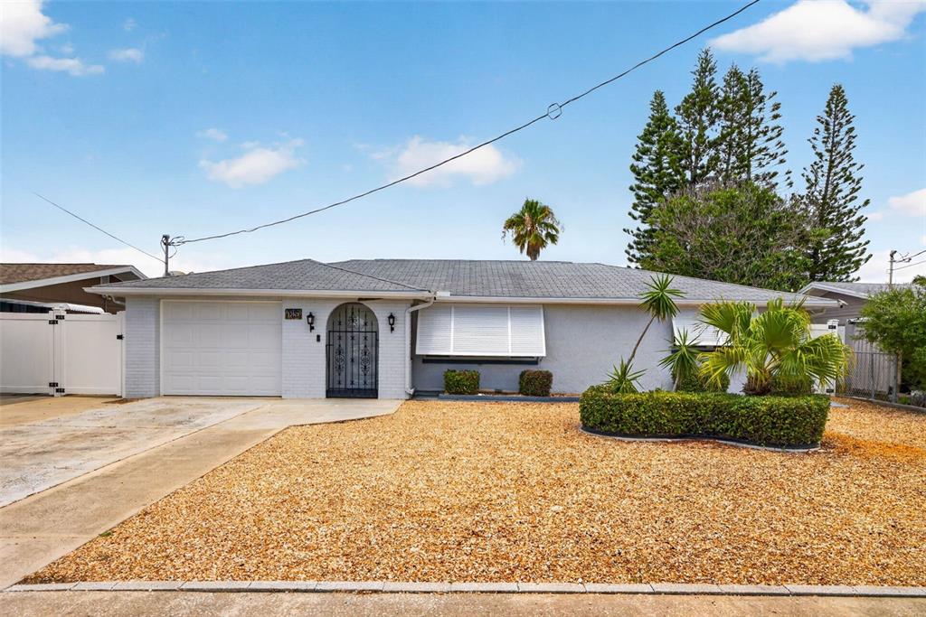 A single-story house with a grey brick exterior, a gravel front yard, and a garage — 13626 JENNITA DRIVE, HUDSON, FL