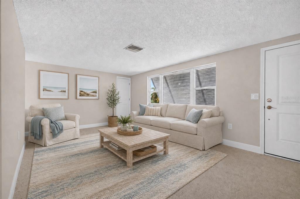 A carpeted living room features a large window, a white door, and a wooden sideboard — 13626 JENNITA DRIVE, HUDSON, FL