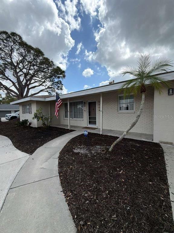 A single-story house with a brick facade, a palm tree, and an American flag — 5004 MEDALIST ROAD, SARASOTA, FL