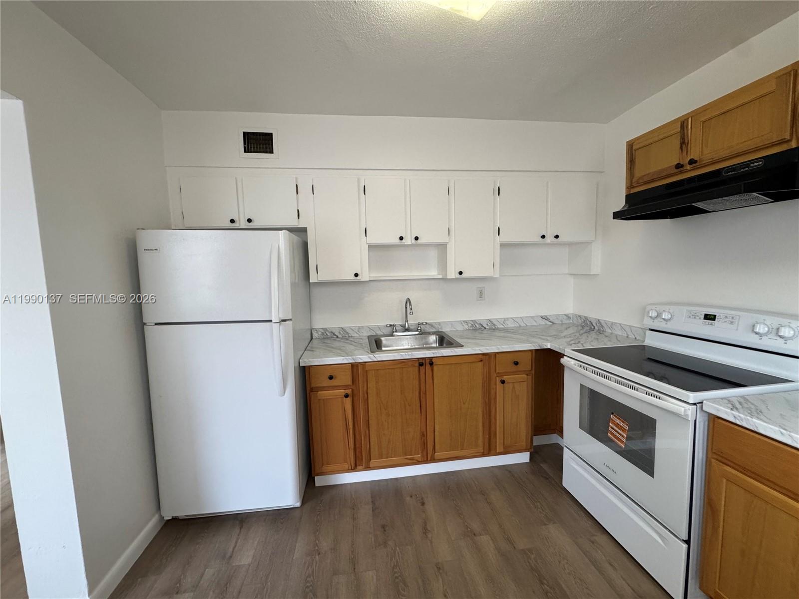 A kitchen features white upper cabinets, wood lower cabinets, white appliances, and marble-patterned countertops — 4080 SW 2nd Ter # 6, Miami FL 33134, MIAMI, FL