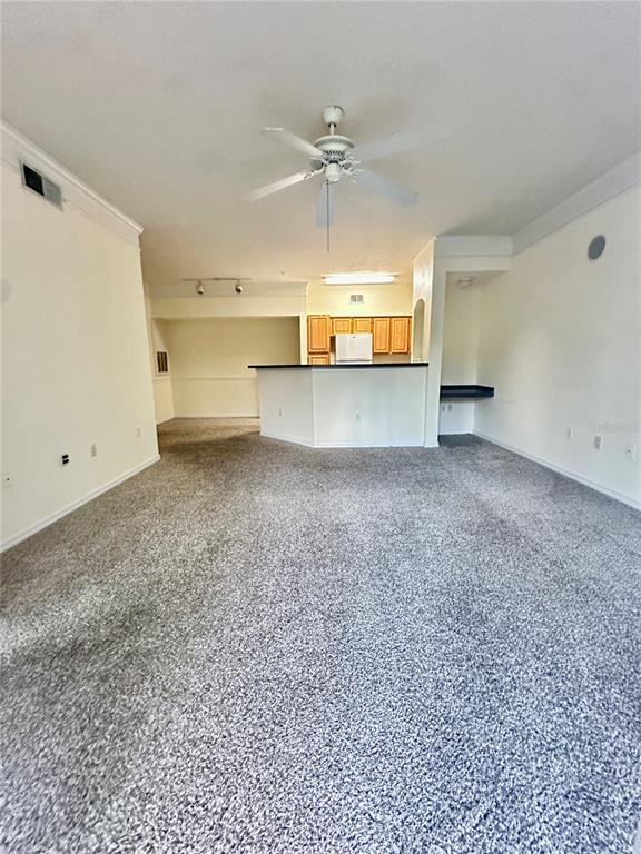 A carpeted living room opens to a kitchen with a breakfast bar and wooden cabinets — 3446 SOHO STREET UNIT 206, ORLANDO, FL