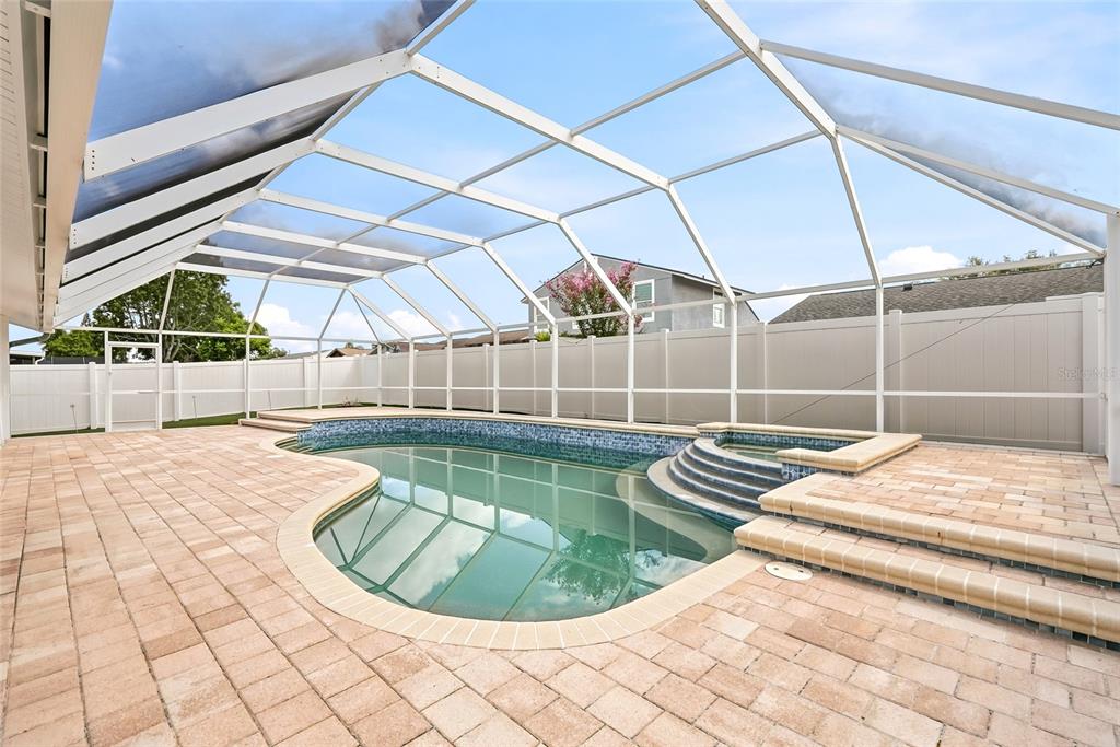 A screened-in swimming pool and spa with paver decking and a white vinyl fence — 12511 CARDIFF DRIVE, TAMPA, FL