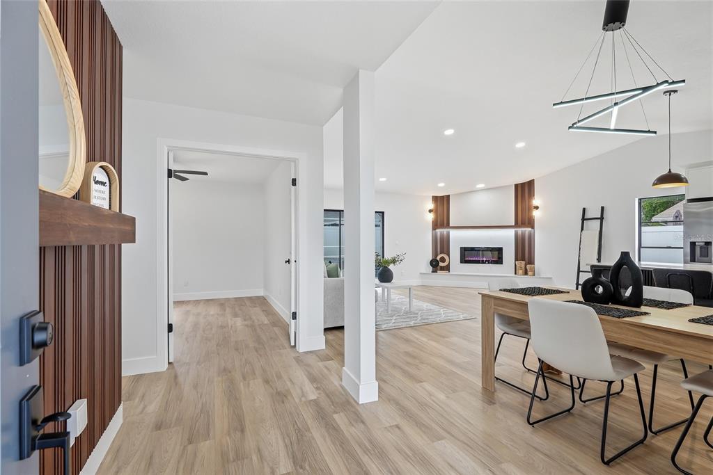 An open-concept living and dining area features light wood flooring, a fireplace, and modern lighting — 12511 CARDIFF DRIVE, TAMPA, FL