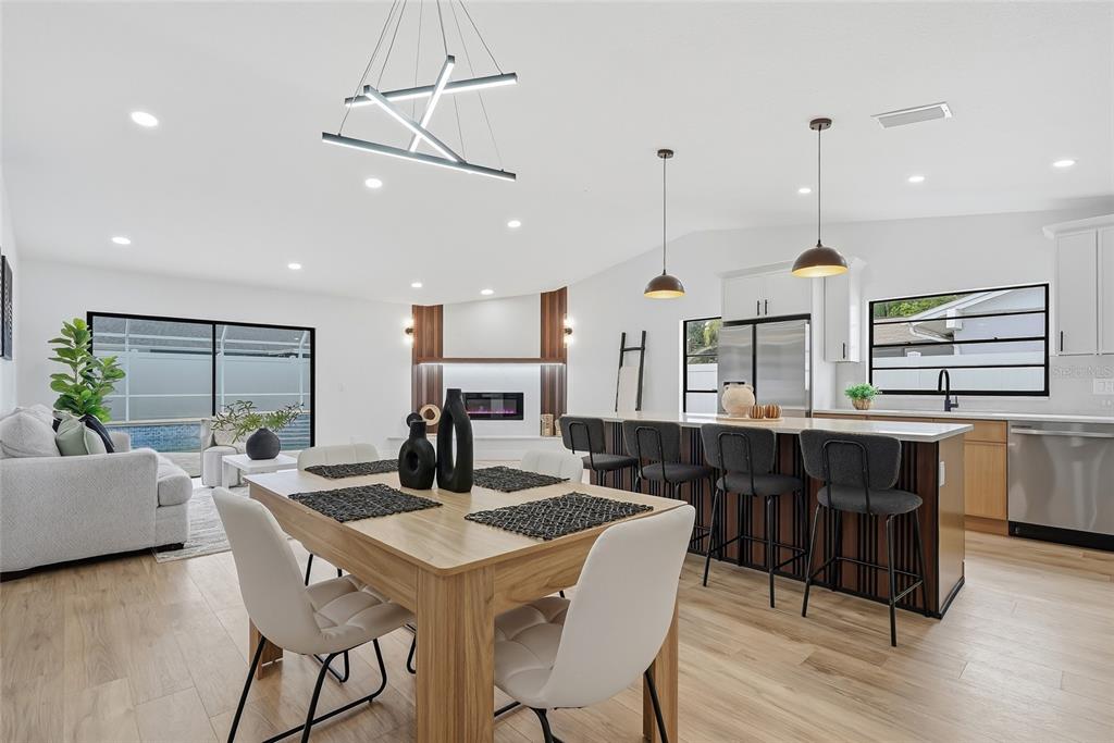 An open-concept living and dining area features a modern kitchen island and a fireplace wall — 12511 CARDIFF DRIVE, TAMPA, FL