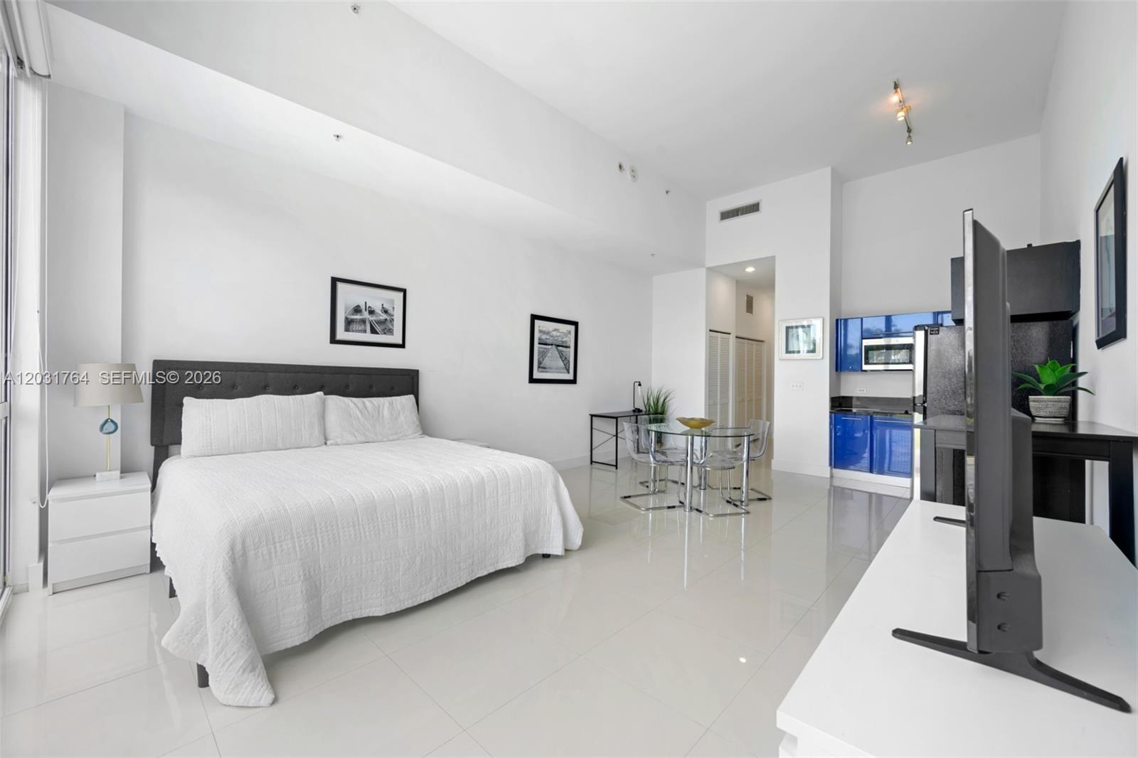 A studio apartment features a bed, a small dining area, and a blue kitchen — 253 NE 2nd St # 231, Miami FL 33132, MIAMI, FL