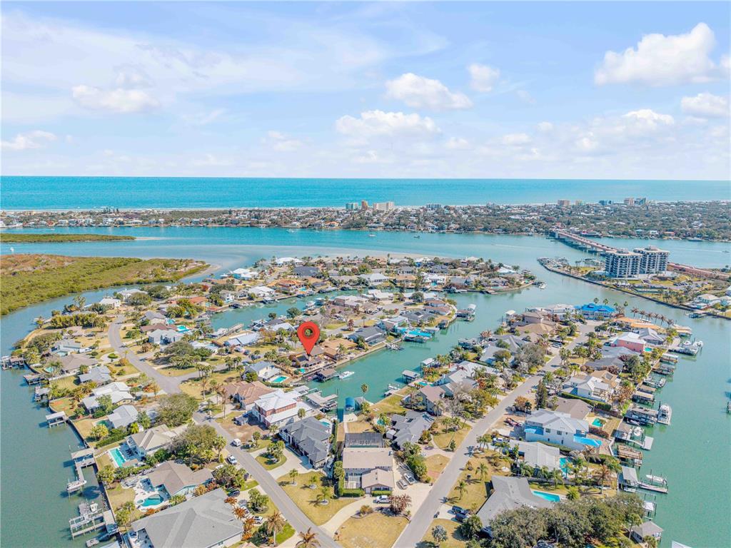 An aerial view shows a waterfront house with a red location pin on a canal — 102 VIA DUOMO, NEW SMYRNA BEACH, FL