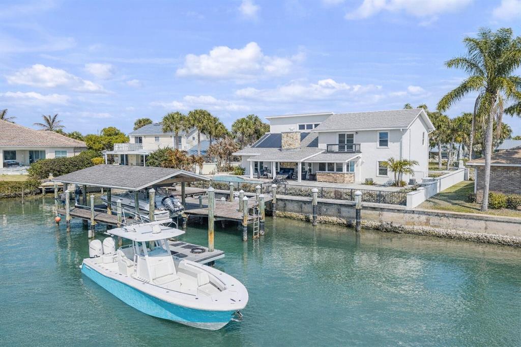 A two-story white house with a boat dock and a boat in the water — 102 VIA DUOMO, NEW SMYRNA BEACH, FL