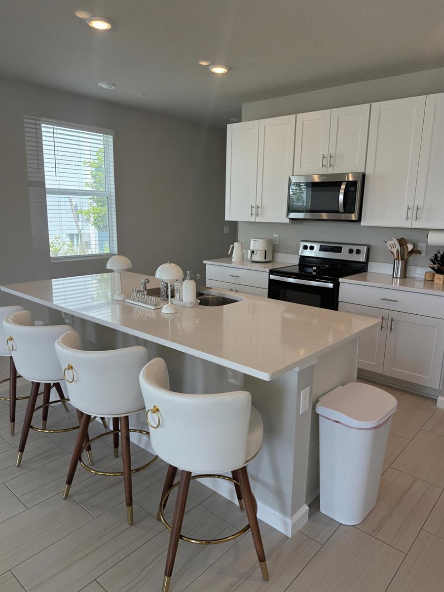 A modern kitchen features white cabinets, a large island with bar stools, and stainless appliances — 389 Salisbury Circle, Fort Pierce FL 34982, FORT PIERCE, FL