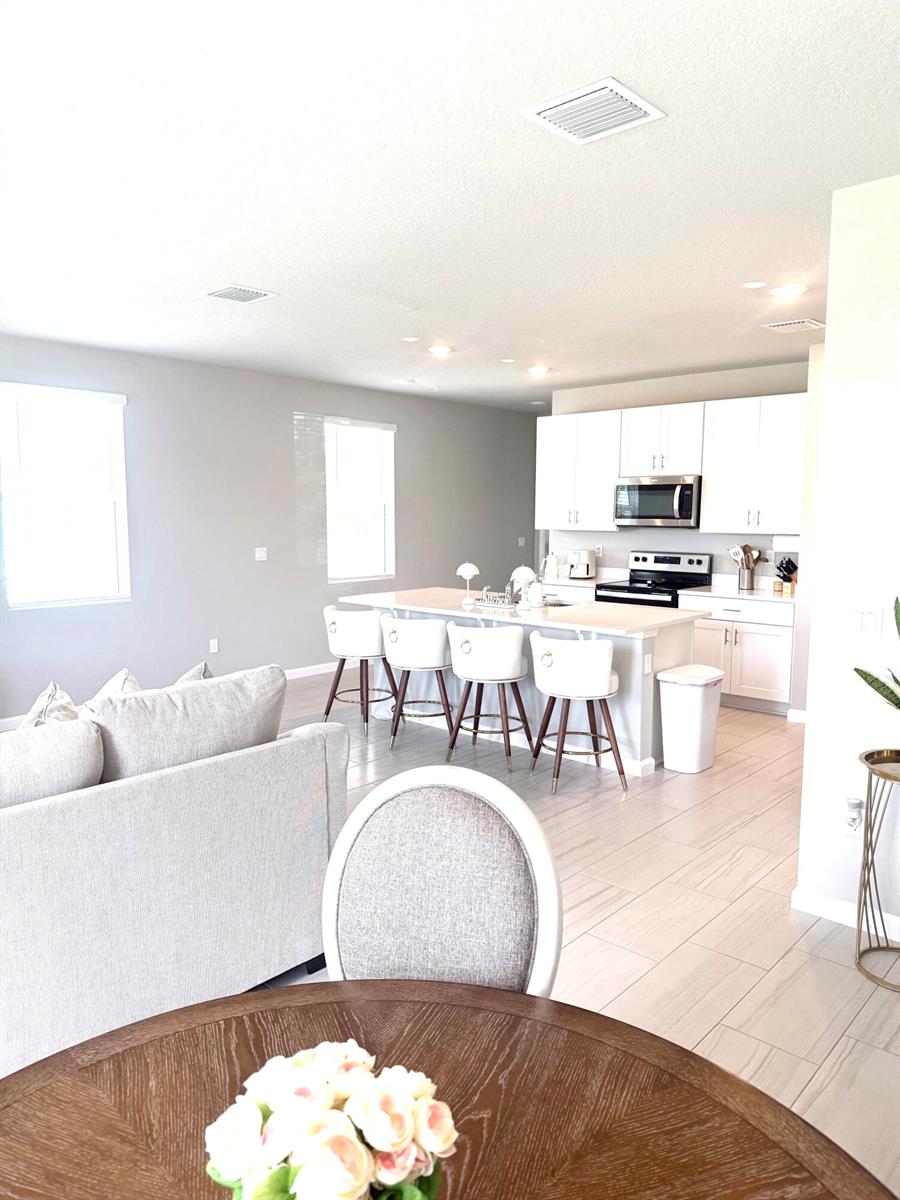 An open-concept kitchen features white cabinetry, a central island with bar seating, and tile flooring — 389 Salisbury Circle, Fort Pierce FL 34982, FORT PIERCE, FL