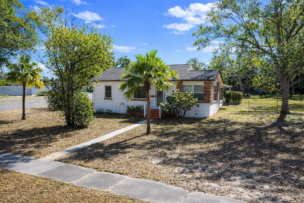 A white single-story house with a stone accent wall and a palm tree in front — 1240 DRUID CIRCLE, LAKE WALES, FL