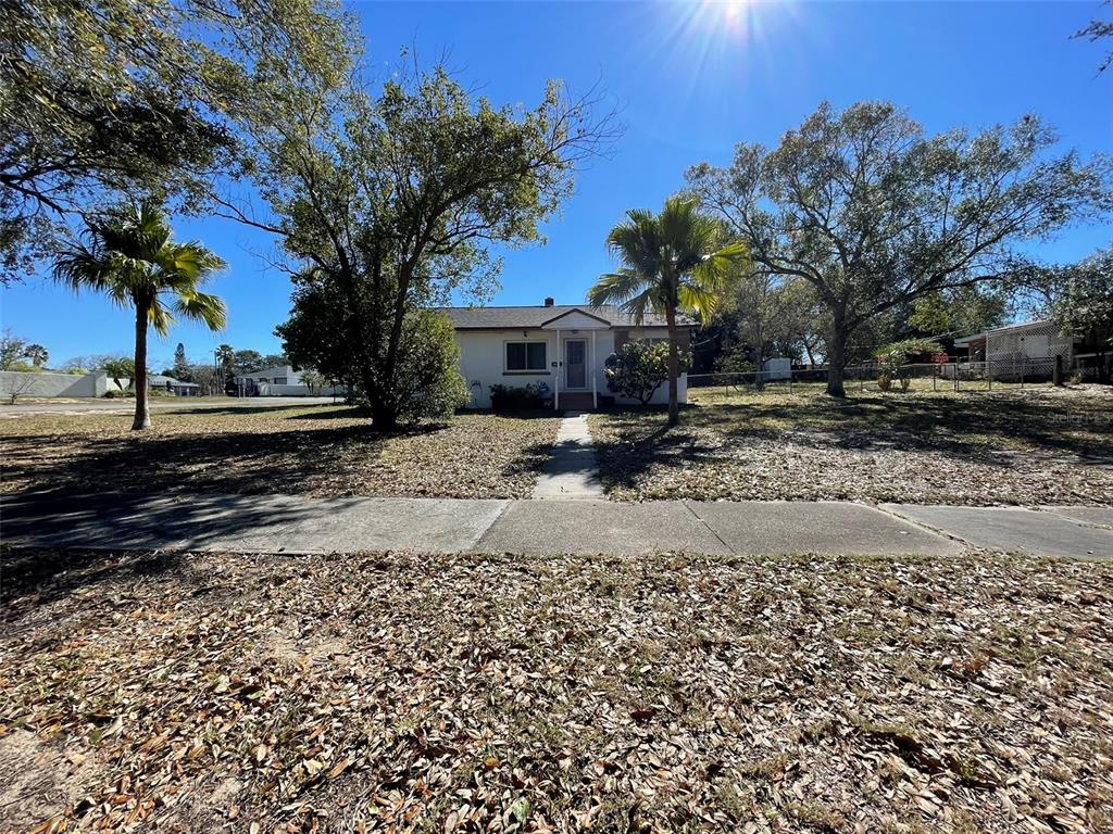 A single-story house with a front walkway stands behind a yard covered in fallen leaves — 1240 DRUID CIRCLE, LAKE WALES, FL