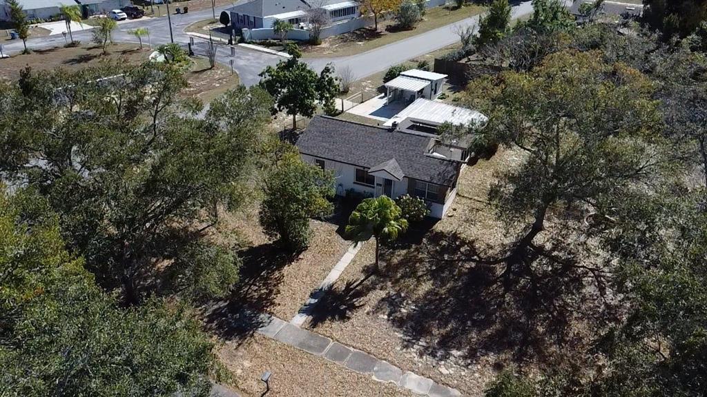 An aerial view shows a single-story house with a dark roof surrounded by mature trees — 1240 DRUID CIRCLE, LAKE WALES, FL